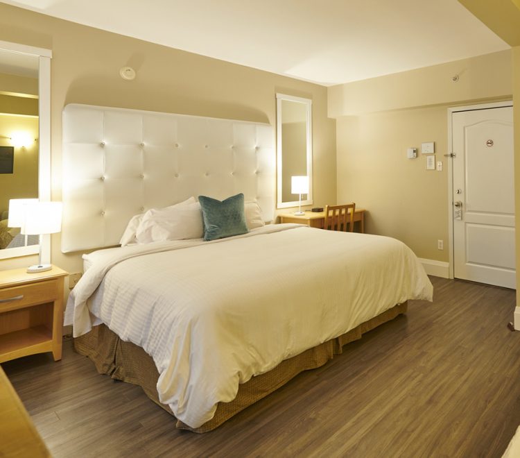 King Sized bed with two side tables and large mirrors in Room 206