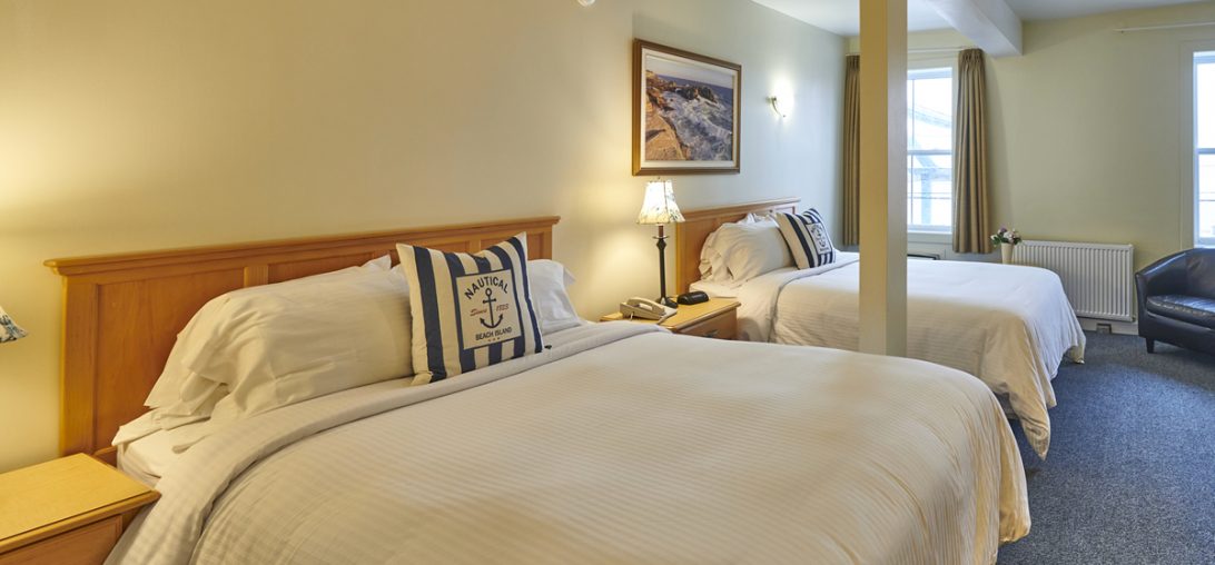 Two Queen sized beds with blue and white nautical themed pillows in Room 211