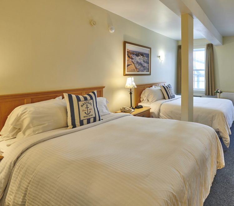 Two Queen sized beds with blue and white nautical themed pillows in Room 211